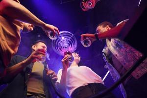 Drinking alcohol. Group of friends having fun in the night club together photo