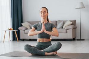 Lotus pose. Young woman with slim body type and in yoga clothes is at home photo