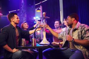 Smoking hookah. Group of friends having fun in the night club together photo