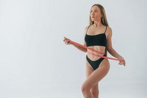 With measuring tape. Woman in underwear with slim body type is posing in the studio photo