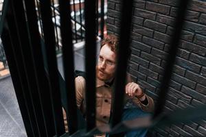 View through steel railings. Man in khaki colored jacket and in jeans is on the stairs on the building outdoors photo