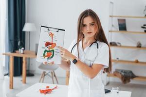 Woman holding illustration. Professional medical worker in white coat is in the office photo