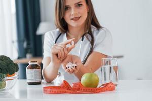 Pills and apple. Professional medical worker in white coat is in the office photo