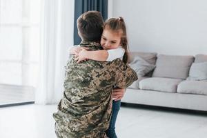 Embracing each other. Soldier in uniform is at home with his little daughter photo