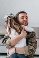 Embracing each other. Soldier in uniform is at home with his little daughter photo