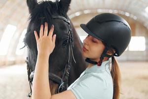 Close up view. A young woman in jockey clothes is preparing for a ride with a horse on a stable photo