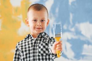 Ukrainian flag colors. Conception of peace. Little boy painting walls in the domestic room photo