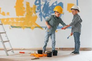 Blue and yellow colored background. Two boys painting walls in the domestic room photo