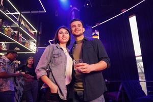 hombre con su novia. grupo de amigos divirtiéndose juntos en la discoteca foto