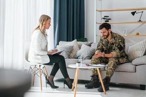 Process of therapy. Soldier is with psychologist indoors photo