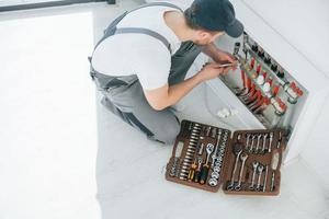 With special tools. Repairman is working indoors in the modern room photo