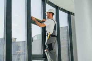 Working with windows. Repairman is indoors in the modern room photo