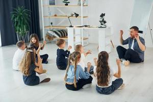 Man teaches gesture language. Group of children students in class at school with teacher photo