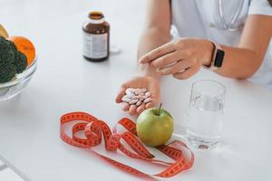 Conception of dieting. Holding apple. Professional medical worker in white coat is in the office photo