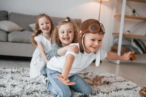 Boy is in aviator glasses. Group of children is together at home at daytime photo