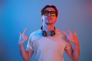 Showing gestures. Man standing in the studio with neon light photo