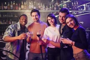 Standing together. Group of friends having fun in the night club photo