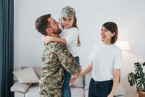 Soldier in uniform is at home with his wife and daughter photo