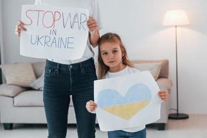 Mother with her little daughter standing with banners with text stop war in Ukrane photo