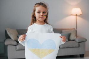 niña sosteniendo una pancarta con una imagen de calor en el color de la bandera ucraniana foto