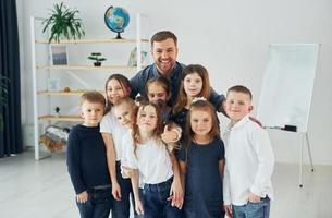 Standing together. Group of children students in class at school with teacher photo