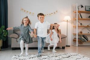 divirtiéndose en la fiesta de cumpleaños. grupo de niños está juntos en casa durante el día foto