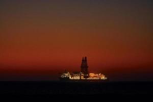 majestuosa vista lejana del barco que está en el océano al atardecer foto