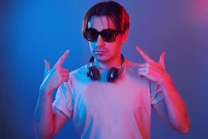 Showing gestures. Man standing in the studio with neon light photo