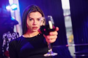 mujer de pie en el club nocturno y sosteniendo un vaso con bebida foto