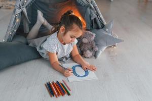 concepción de la educación. linda niña jugando en la carpa que está en la habitación doméstica foto