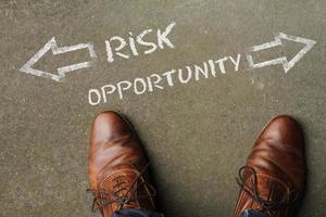 Top view on a man standing in front of the words Risk and Opportunity with arrows pointing to the left and right side of the picture photo