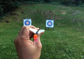 Hand holding an arrow with two targets in the background photo