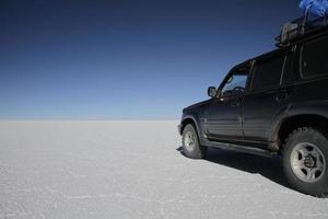 Uyuni, Bolivia - July 13, 2016 - A jeep stands in the middle of the vast white desert of the Uyuni salt flats in Bolivia. photo