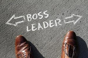 The words Boss and Leader written on the floor with two arrows pointing in opposite directions photo