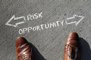 Top view on a man standing in front of the words Risk and Opportunity with arrows pointing to the left and right side of the picture photo