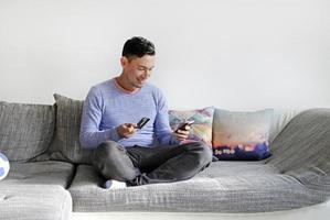 Man on couch using smartphone and credit card photo