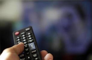 Holding a TV remote control and switching channels photo