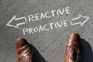 The words Reactive and Proactive written on the floor with arrows pointing in opposite directions photo