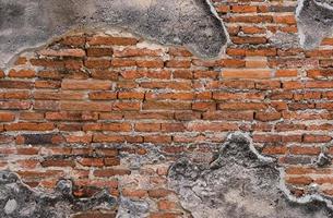 Vintage Wethered Concrete Wall That Cracked and Exposed Red Brick inside at Exterior of Old Building photo