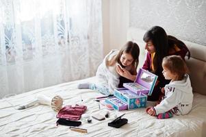 Mother and daughters doing makeup on the bed in the bedroom. photo