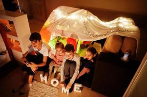 Kids in tent waching tv at night home. Hygge mood. photo