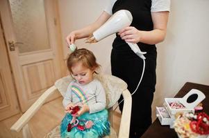 mamá con hija haciendo juntos la rutina diaria. la madre está cepillando y secando el cabello del niño después de la ducha. foto