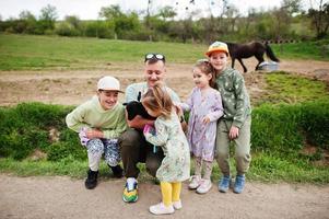 Father with four kids on an animal eco farm hold baby sheep lamb in hand. photo