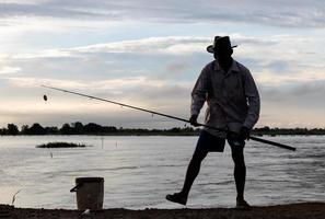 silueta de hombres tailandeses de pie pescando. foto