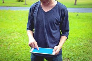 parte del cuerpo. por la mañana, un hombre parado y jugando con una tableta en un parque público. foto