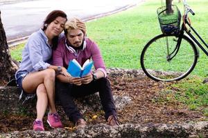 A man read a book and woman read a book too.They are in love and relax time  in public park Thailand.they are honeymoon  day. photo