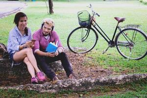 A man read a book and woman read a book too.They are in love and relax time  in public park Thailand.they are honeymoon  day. photo