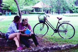 A man read a book and woman read a book too.They are in love and relax time  in public park Thailand.they are honeymoon  day. photo