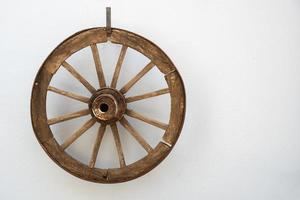 Vintage wooden cartwheel hangs on a white wall photo