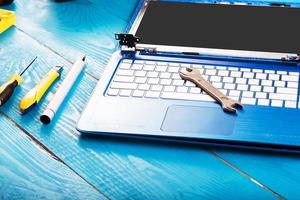 Wizard repairs laptop with tools and hands on the blue wooding table. top view photo